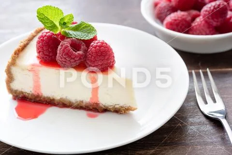Slice of classical cheesecake with raspberries and berry sauce on white plate Stock Photos