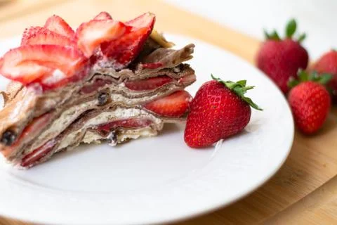 A slice of crepe layer cake with whipped cream and strawberry Foto stock