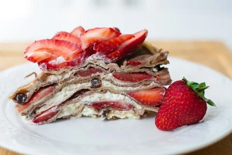 A slice of crepe layer cake with whipped cream and strawberry Stock Photos