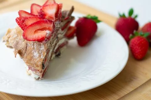 A slice of crepe layer cake with whipped cream and strawberry Stock Photos