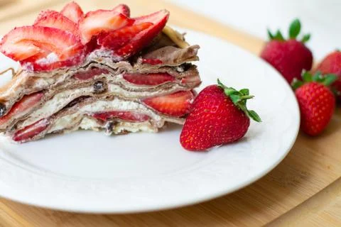 A slice of crepe layer cake with whipped cream and strawberry Stock Photos