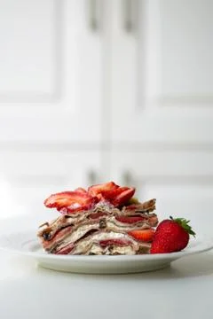 A slice of crepe layer cake with whipped cream and strawberry Stock Photos
