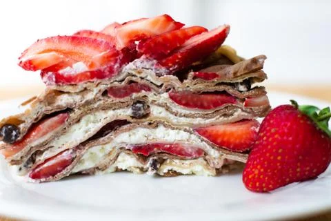 A slice of crepe layer cake with whipped cream and strawberry Stock Photos