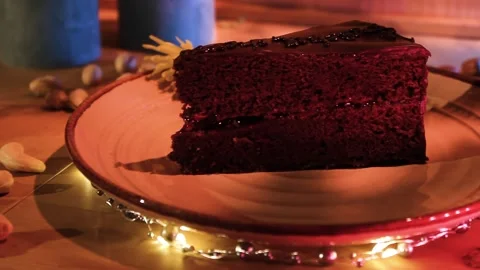 Slice Of Dark Chocolate Cake Served In The Table With Fairy Lights. - Video stock 171342622