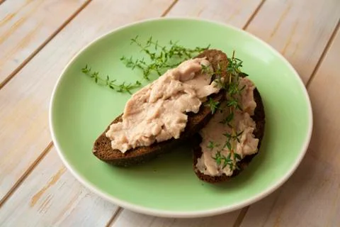Slice of dark wheat bread and liver pate on green plate Stock Photos