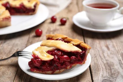 Slice of delicious fresh cherry pie on wooden table, closeup Stock Photos