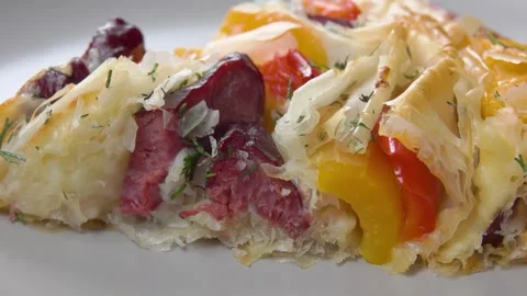 A slice of a delicious pie made with filo pastry is lying on a plate. Stock-Footage 327459279