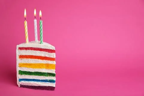 Slice of delicious rainbow cake with candles on color background Stock Photos