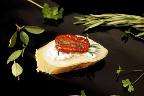 Slice of dried tomato on bread piece on black background Stock Photos
