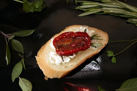 Slice of dried tomato on bread piece on black background Foto stock