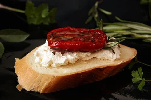 Slice of dried tomato on bread piece on black background Stock Photos