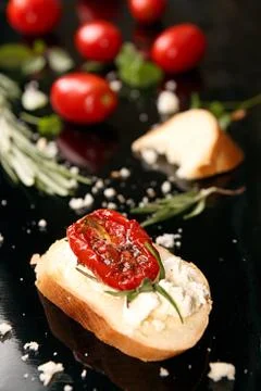 Slice of dried tomato on bread piece on black background Stock Photos