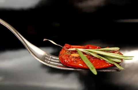 Slice of dried tomato on fork on black background Stock Photos