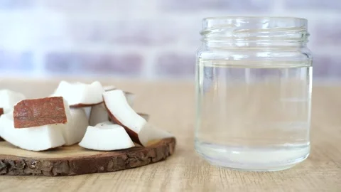 Slice of fresh coconut and bottle of oil on a table  Stock Footage 297042181