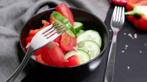 A slice of fresh cucumber is spinning on a fork. Blurred background. Salad. Stock Footage 154456749