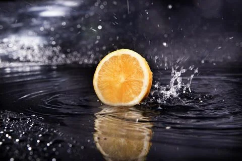 Slice of fresh lemon over the dark background with water Stock Photos