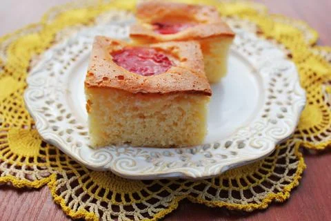 Slice of fresh plums cake on white plate Stock Photos