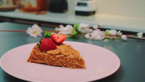 Slice of golden brown cake garnished with strawberries on pink plate indoors Stockbeeldmateriaal 342870850