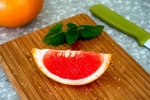 Slice of grapefruit and mint on cutting board Stock Photos