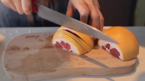 Slice the grapefruit thinly on the cutting board Stock Footage 126499616
