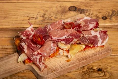 Slice of homemade rectangular pizza with onion, raw parma and dehydrated toma Stock Photos