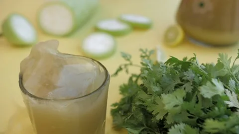 A slice of juicy lemon falling inside a glass of refreshing bottle gourd squa... Stock Footage 155612959