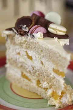 Slice of Layered Celebration Cake with Fruit Filling and Macaron Topping Stock Photos