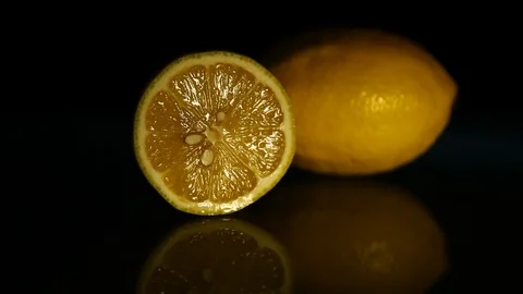 A slice of lemon and a whole lemon on a dark table. HD Stock Footage 89762317