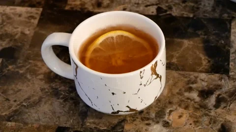 Slice of Lemon Being Dropped Into a Teacup Stock Footage 161670778