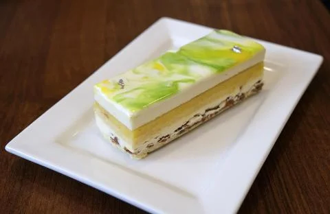 Slice of lemon cake on a square white plate in a cafe Stock Photos