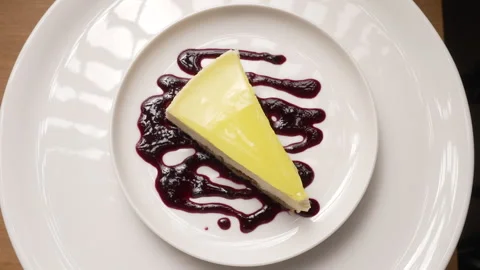 Slice of lemon cheesecake with a berry sauce drizzle rotating Stock Footage 333582432