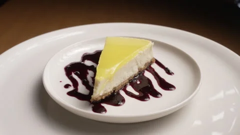 Slice of lemon cheesecake with a berry sauce drizzle rotating Stock Footage 333593483