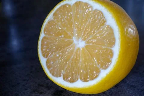 A slice of lemon is cut in half and placed on a counter Stock Photos