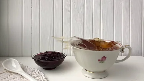 A slice of lemon drops into a cup of tea Видео 82693323