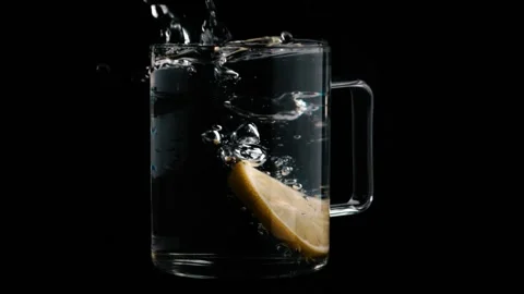 A slice of lemon falls into a glass filled with clear water in slow motion Stock-Footage 137855603