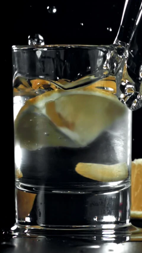 A slice of lemon falls into a glass of vodka. Filmed on a high-speed camera at Stock Footage 335367880
