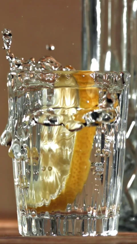 A slice of lemon falls into a glass of vodka. Filmed on a high-speed camera at Stock Footage 335368504