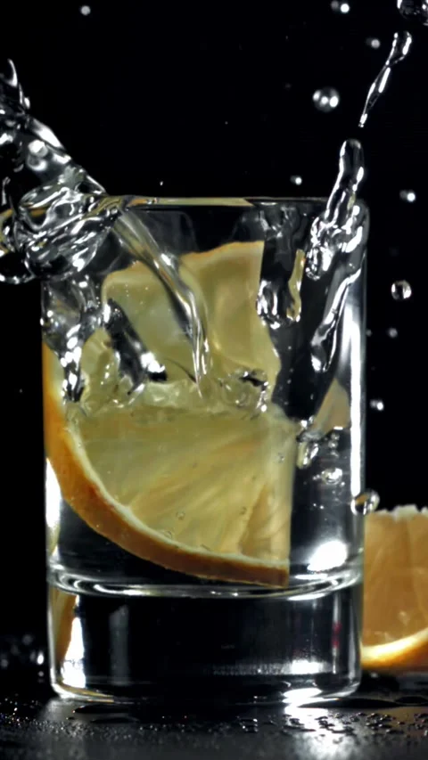 A slice of lemon falls into a glass of vodka. Filmed on a high-speed camera at Stock-Footage 335370566