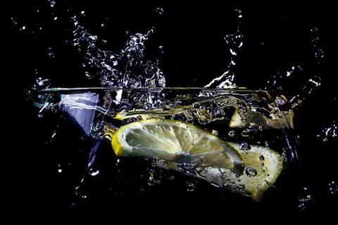 A slice of lemon falls into the water Stock Photos