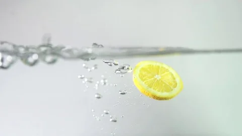 A slice of lemon falls into water with a splash Stock Footage 79540724