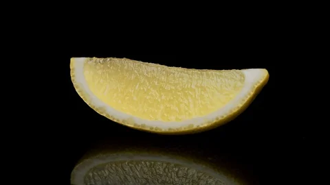 A slice of lemon rotating on a black background 動画素材 128720105