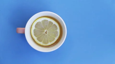 Slice of lemon swirling in a teacup, from above on a blue background Stock Footage 131764016