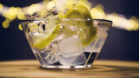 Slice of lemon,lime dropped into bowl full of water and ice cubes Stock Footage 128554166