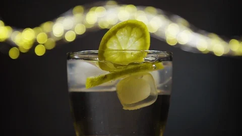 Slice of lemon,lime dropped into glass full of water and ice cubes Stock Footage 128431473