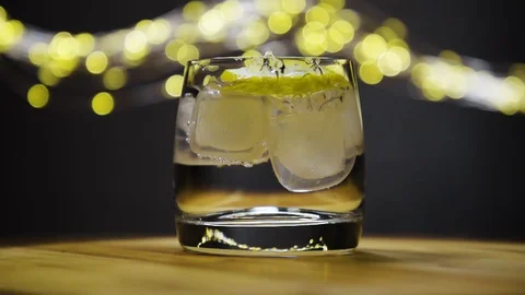 Slice of lemon,lime dropped into glass full of water and ice cubes Stock Footage 128442034