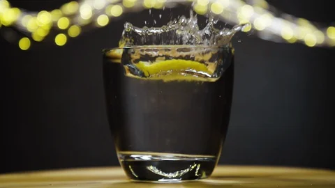 Slice of lemon,lime dropped into glass full of soda Stock Footage 128443064