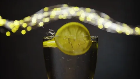 Slice of lemon,lime dropped into glass full of soda Stock Footage 128443543