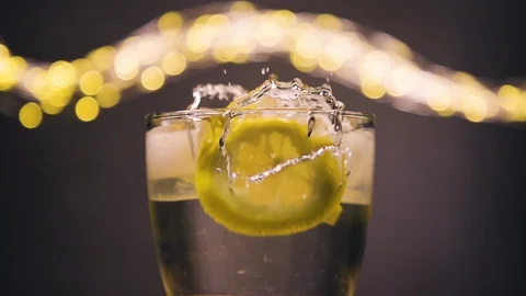 Slice of lemon,lime dropped into glass full of soda Stock Footage 128698581