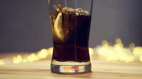Slice of lemon,lime dropped into glass full of Cola and ice cubes Stock Footage 128924200