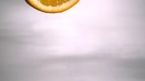 Slice of lime falling into the water and causing a splash crown in slow motion Stock Footage 81230447